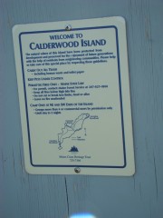 sign: "Welcome to Calderwood Island, . . ., Maine Coast Heritage Trust" near a beach on Calderwood Island near the eastern end of the Fox Islands Thoroughfare